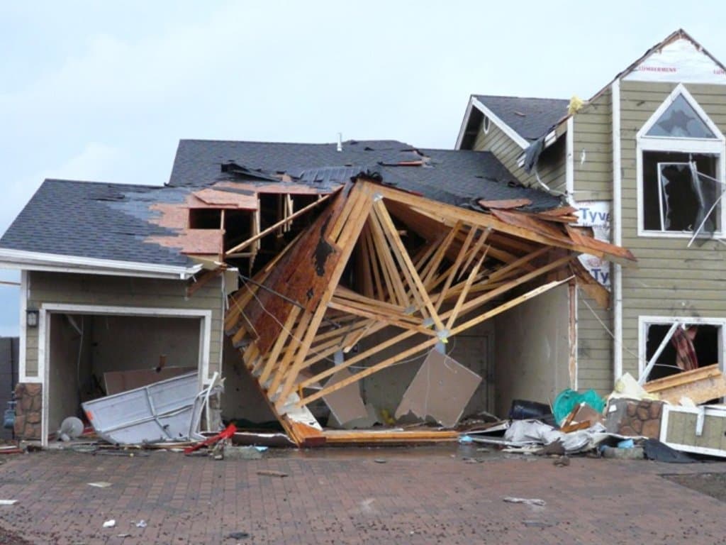 Home with collapsed roof trusses and structural damage after a tornado