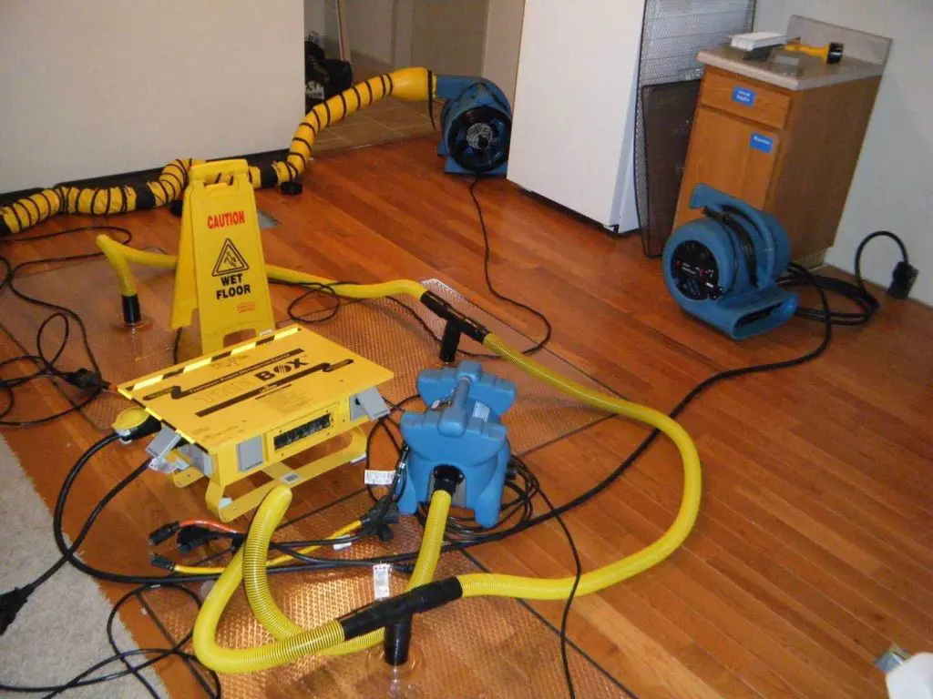 Drying equipment and ducting set up on a hardwood floor during water damage mitigation