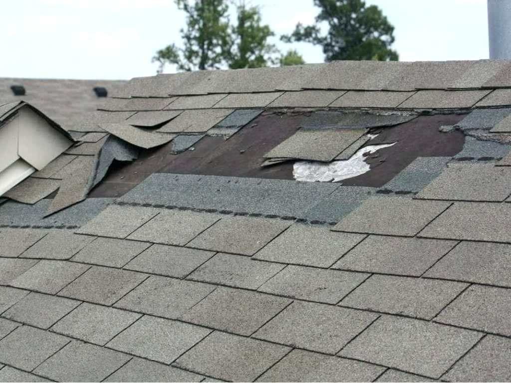 Roof with shingles torn away by high winds exposing the underlayment beneath
