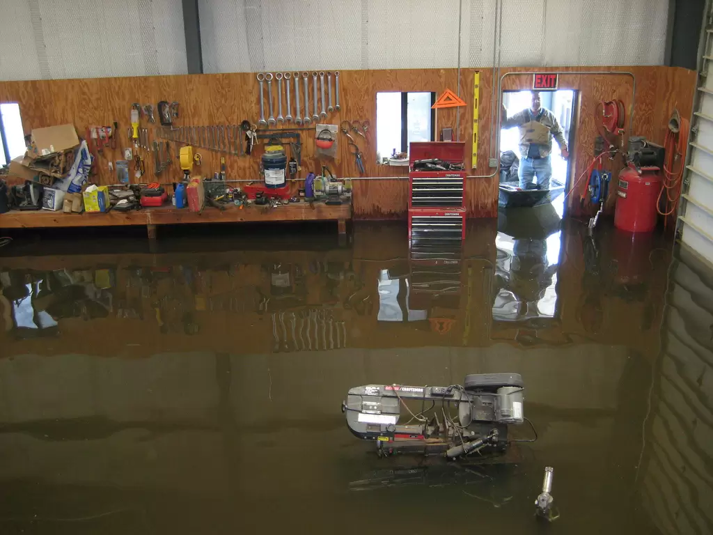 Interior of a flooded building with standing water covering the floor and equipment