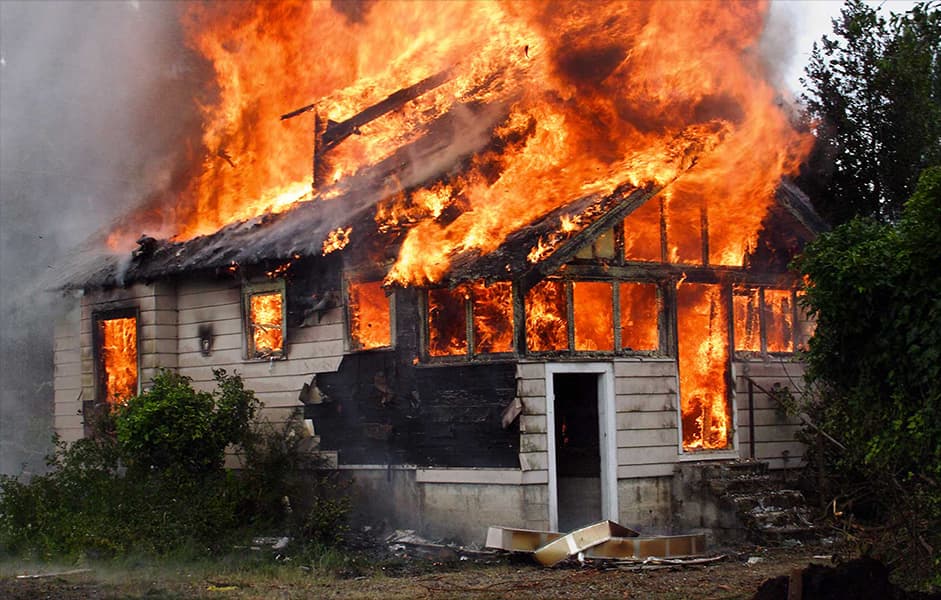 Single-storey house fully involved in flames, illustrating residential fire risk